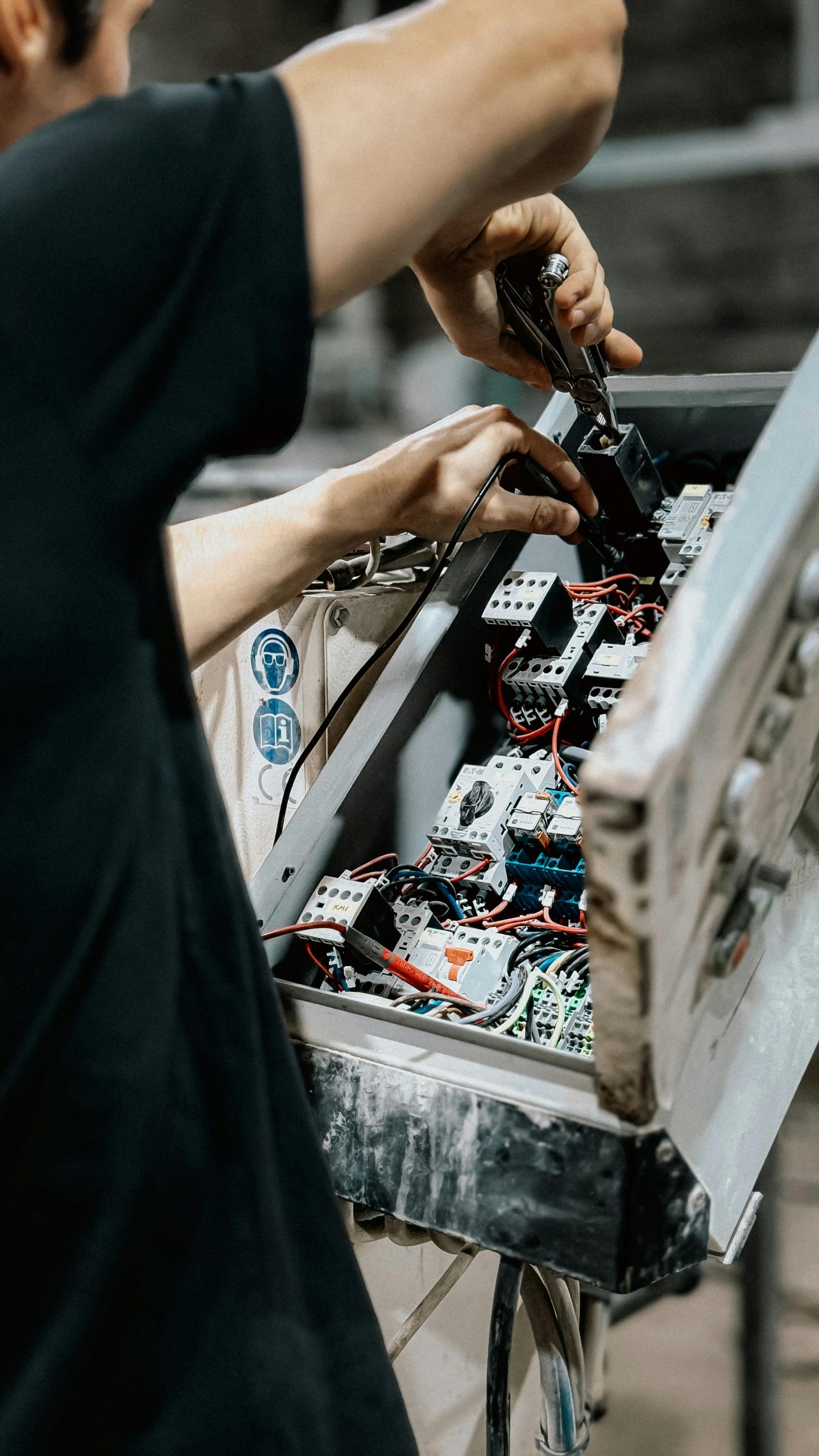 Technician adjusting wires in an electrical control panel for maintenance
